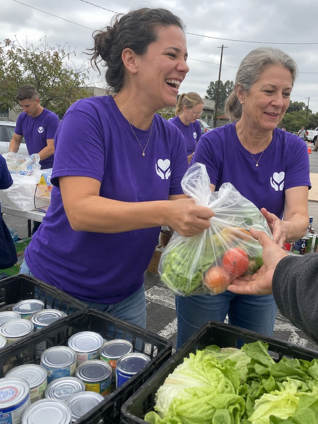 Volunteers in custom-printed logo tees handing out groceries at a community food drive